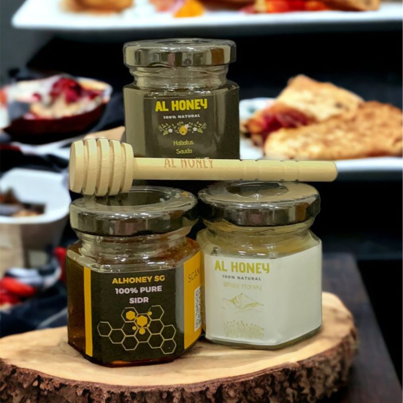 Three Mini Jars of Al Honey with delicious food in the background