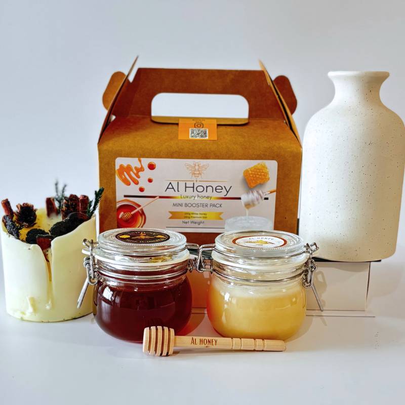 Front photo of al honey booster pack shows white honey and premium sidr honey with a wooden dipper