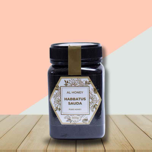 Al Honey Habatus Sauda bottle on a table with pink and white background to showcase the bottle