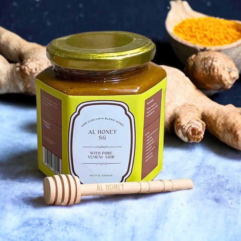 Al Honey's delicious Sidr curcumin blend. Showing the product and glass bottle along with wooden stick. Organic ginger is showing in the background.