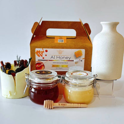 Front photo of al honey booster pack shows white honey and premium sidr honey with a wooden dipper 