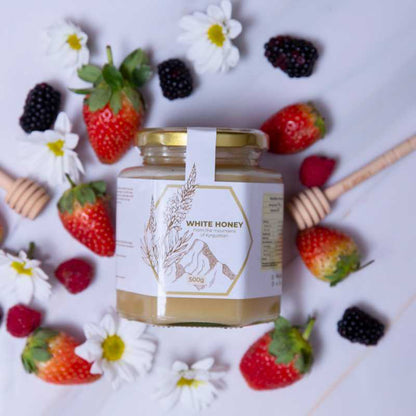 Front view from the top of Al Honey white Honey with fruits and wooden dipper 