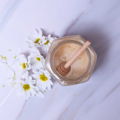 Top view of Al Honey white Honey with flowers and a wooden dipper 